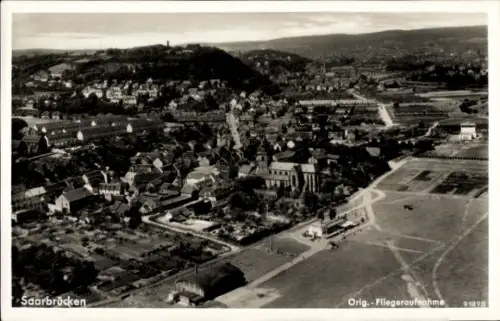 Ak Saarbrücken im Saarland, Luftaufnahme von  viele Gebäude, grüne Landschaft