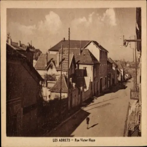 Ak Les Abrets Isère, Straße mit Häusern, Rue Victor Hugo, ein Mann auf der Straße