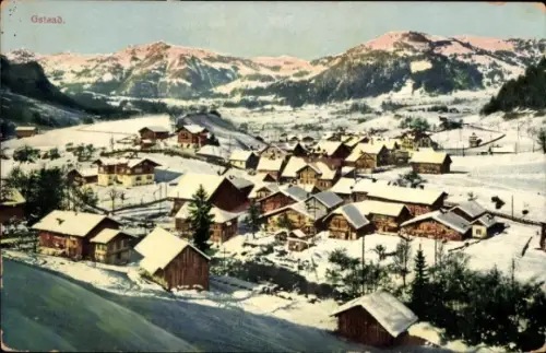 Ak Gstaad Saanen Kanton Bern, Schneebedeckte Landschaft, typisches Chalet-Dorf, Berge im Hintergr
