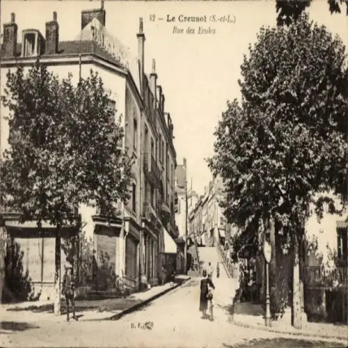 Ak Le Creusot Saône et Loire, Straße mit Bäumen, Häusern, Beschriftung Rue des Ecoles