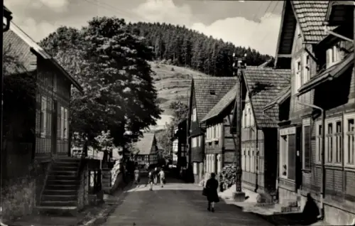 Ak Gießübel in Thüringen, Ruhige Straße, Fachwerkhäuser, Bäume, Menschen, Berge im Hintergrund