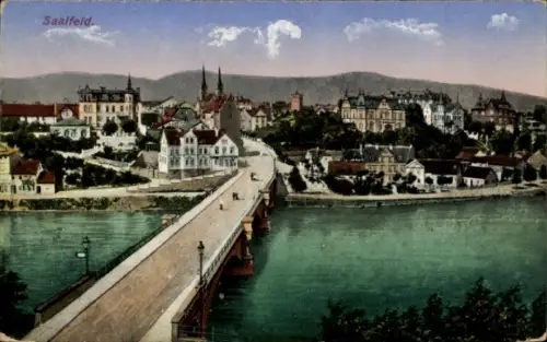 Ak Saalfeld an der Saale, Gißratal, Brücke, Häuserfront, Fluss, Hügel im Hintergrund, farbige 