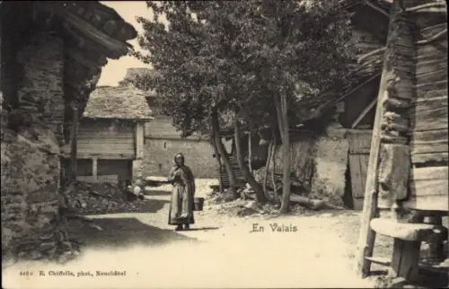 Ak Kanton Wallis, Dorfmotiv, Holzhäuser, Frau mit Eimer