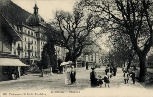 Ak Interlaken Kanton Bern Schweiz, Interlaken Höheweg, Menschen mit Schirmen, Bäume, Gebäude, 197