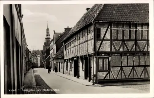 Ak Ystad Schweden, Straße mit Fachwerkhäusern, Kirchturm sichtbar, Menschen auf der Straße
