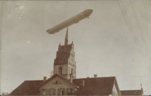 Foto Ak Friedrichshafen am Bodensee, Zeppelin-Luftschiff über der Stadt, Kirchturm