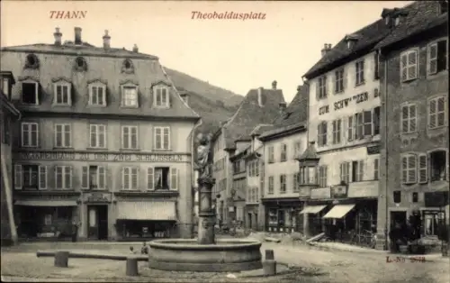 Ak Thann Elsass Haut Rhin, Theobaldusplatz, Brunnen, alte Gebäude, Geschäfte, schwarz-weiß Bild