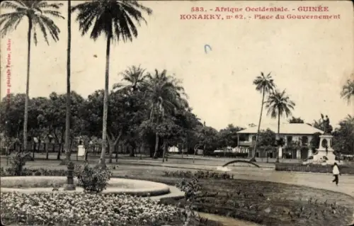 Ak Conakry Konakry Guinea, Platz du Gouvernement, Palmen, Statue, Blumenbeet,  