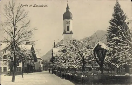 Ak Garmisch Partenkirchen in Oberbayern, Schneebedeckte Straße, Kirche mit Uhrturm, Bäume,  Gebäu