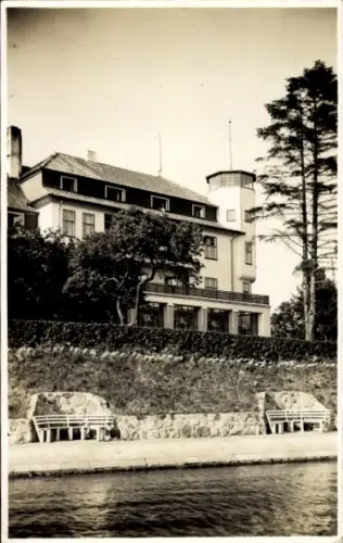 Ak Neustadt in Holstein, Großes Gebäude mit Turm, Sitzbänke am Wasser, Bäume, Himmel