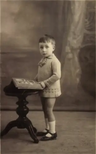 Foto Ak Kinderportrait, Junge mit Album, Ansichtskarten-Geschichte