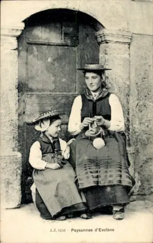 Ak Evolène Kanton Wallis, Zwei Frauen in Tracht sitzen vor einer Tür.