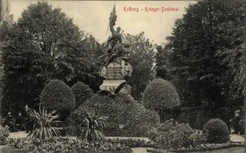 Ak Kołobrzeg Ostseebad Kolberg Pommern, Kolberg Krieger-Denkmal, Statue mit Fahne, Bäume, Sträuch