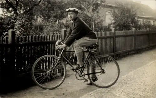 Foto Ak Berlin, junger Mann auf einem Fahrrad, Gartenzaun