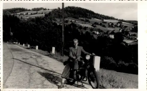 Foto Mann mit Motorrad am Rand einer Landstraße, bergige Landschaft, August 1953