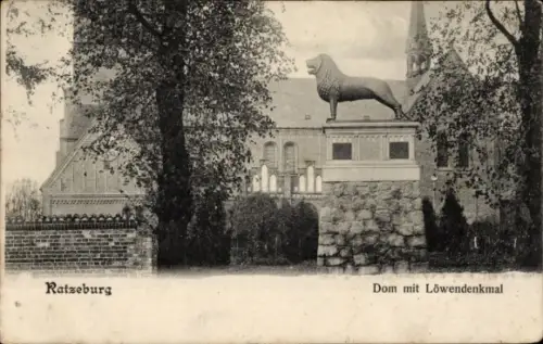 Ak Ratzeburg im Herzogtum Lauenburg,  Dom mit Löwendenkmal, Statue eines Löwen, Bäume im Vordergr
