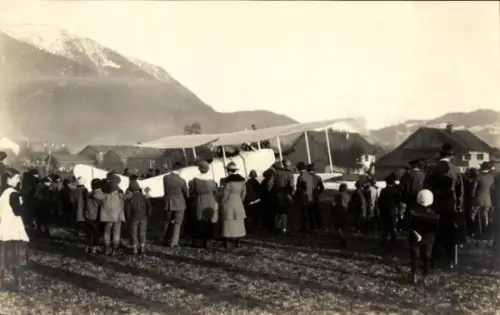 Foto Flugzeug, Doppeldecker auf einem Feld im Gebirge, Schaulustige