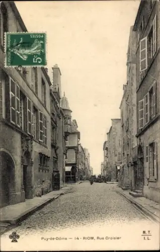 Ak Riom Puy de Dôme, Straße mit Kopfsteinpflaster, alte Gebäude, ein paar Menschen