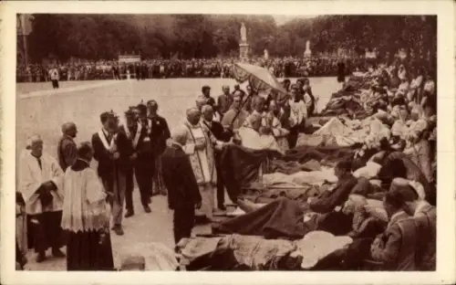 Ak Lourdes Hautes Pyrénées, Kranke liegen auf Bänken, Priester segnet, Menschenmenge im Hintergru