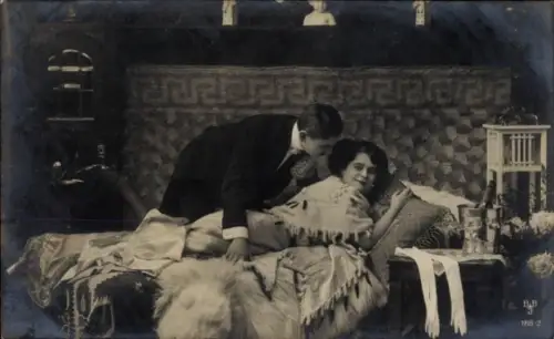 Ak Liebespaar, Mann im Smoking und Frau in einem eleganten Kleid auf einem Bett