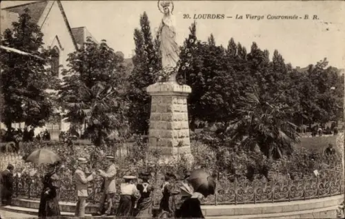 Ak Lourdes Hautes Pyrénées, Statue der Jungfrau Maria, Menschen mit Regenschirmen, Blumenbeete