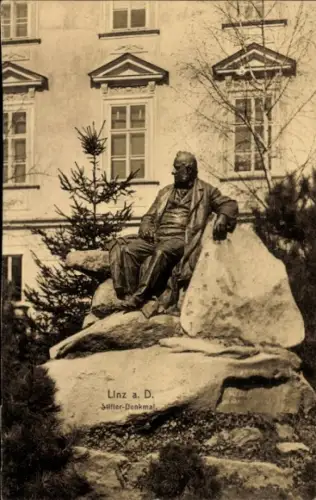 Ak Linz an der Donau Oberösterreich, Denkmal eines sitzenden Mannes, Bäume, Gebäude im Hintergrun