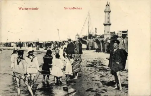Ak Ostseebad Warnemünde Rostock, Strandleben,  Kinder am Wasser, Leuchtturm im Hintergrund