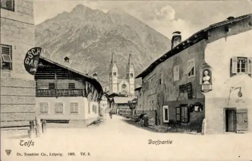 Ak Telfs in Tirol, Dorfpartie,  Berge im Hintergrund, Geschäfte, Straßenansicht