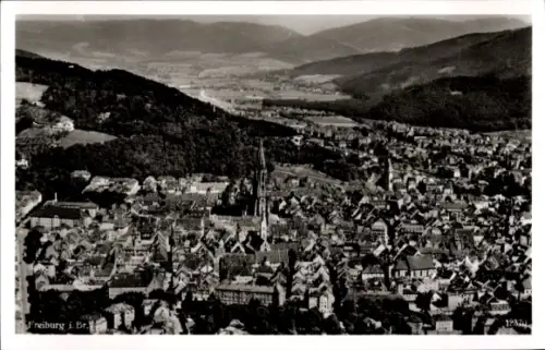 Ak Freiburg im Breisgau, Luftaufnahme von Freiburg, Stadtansicht, Berge im Hintergrund,  Gebäude
