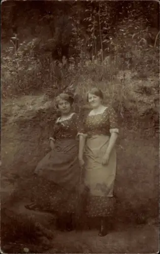 Foto Ak Zwei junge Frauen in Kleidern mit Schürzen, Standportrait