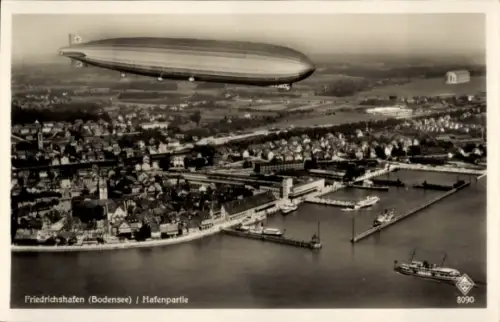 Ak Friedrichshafen am Bodensee, Fliegeraufnahme, Zeppelin über dem Ort, Hafen
