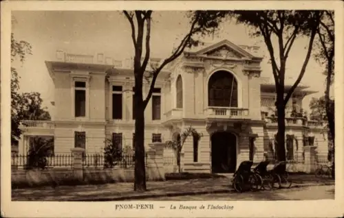 Ak Phnom Penh Kambodscha, Zweistöckiges Bankgebäude mit Portikus und Balkon, Bäume im Vordergrund