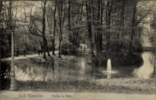 Ak Bad Nauheim in Hessen, Teich mit Fontäne, Uferweg mit Spaziergängern, hohe Bäume, Straßenlater