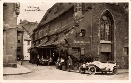 Ak Nürnberg, Schild 'Bratwurstglöcklein', Außentische mit Personen, offenes Auto rechts