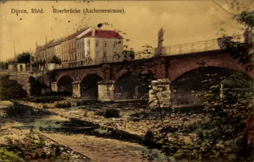 Ak Düren im Rheinland, Steinbrücke mit Bögen, Flussbett mit Vegetation, mehrstöckiges Haus, Statu