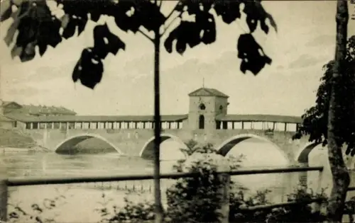 Ak Pavia Lombardia, Überdachte Brücke mit Bögen, mittlerer Turm, Fluss, Uferbepflanzung, Vordergr