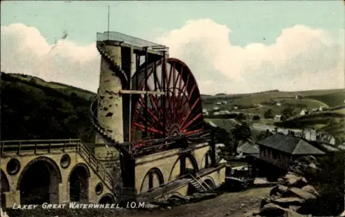 Ak Laxey Isle of Man, großes rotes Wasserrad an steinernem Turm, Bogenfundament, Gebäude, Hügel
