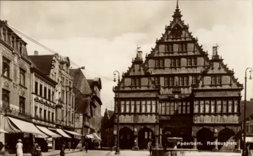 Ak Paderborn in Westfalen, Gestuftes Giebelgebäude vorn, Ladenzeile mit Markisen links, Passanten