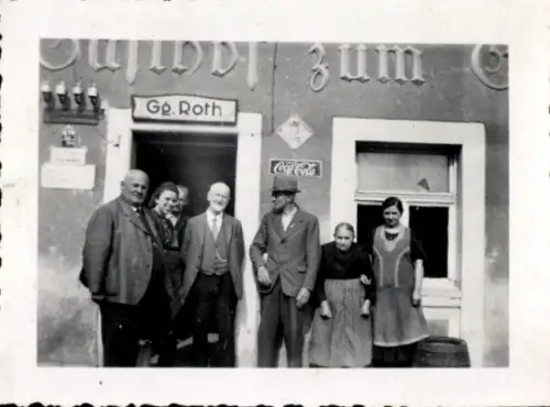 Foto Menschen stehen vor einem Gasthaus