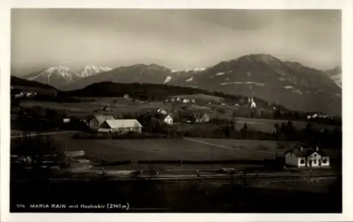Ak Maria Rain in Kärnten, Bergkette mit schneebedeckten Gipfeln, Dorf mit Kirche, verstreute Häus