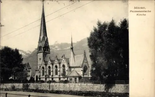 Ak Meran Merano Südtirol, Protestantische Kirche mit hohem Turm, Bäume rechts, Mauer mit Zaun vor