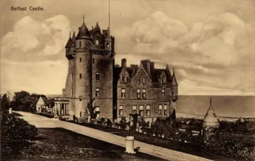 Ak Belfast Nordirland, großes Gebäude mit rundem Turm, Weg vorn, Meer hinten, Personen