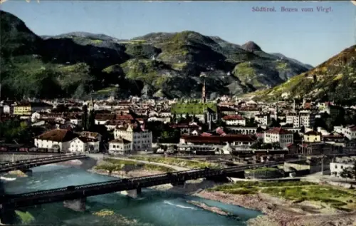 Ak Bozen Bolzano Südtirol, Fluss mit Brücken, Stadtkern mit hohem Kirchturm, viele Häuser, Berge 