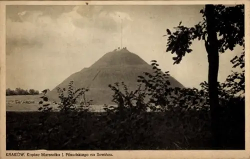 Ak Kraków Krakau Polen, Großer grasbewachsener Hügel mit Mast, winzige Personen oben, Büsche und 