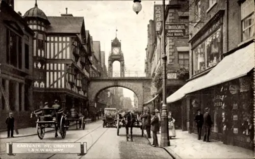 Ak Chester Cheshire England, Straße mit Bogen und Turmuhr, Pferdekutschen und frühe Autos, Ladenf