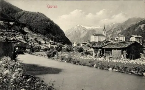 Ak Kaprun in Salzburg, Fluss, Ufervegetation, Holzschuppen rechts, Dorfhäuser, Kirche mit Turm, B