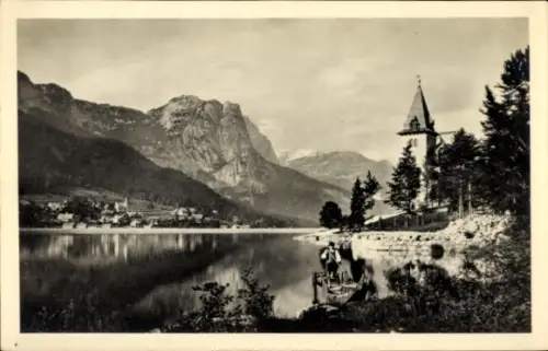 Ak Grundlsee Salzkammergut Steiermark, See mit Bergkulisse, Kirche mit hohem Turm am rechten Ufer