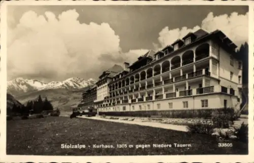 Ak Stolzalpe Murau Steiermark, Mehrstöckiges Kurhaus mit langen Balkonen, Wiese vorn, verschneite