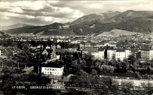 Ak Leoben Steiermark, Stadtpanorama, Berge im Hintergrund, Kirchturm, Flussufer, Bäume, Wohnhäuse