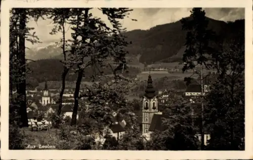 Ak Leoben Steiermark, Kirchturm und Häuser, Bäume im Vordergrund, Berge im Hintergrund